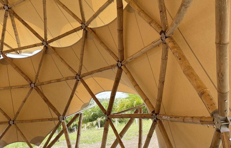 An interior photo of a bamboo dome using tensile fabric as an enclosing wall, with a gap for passing through